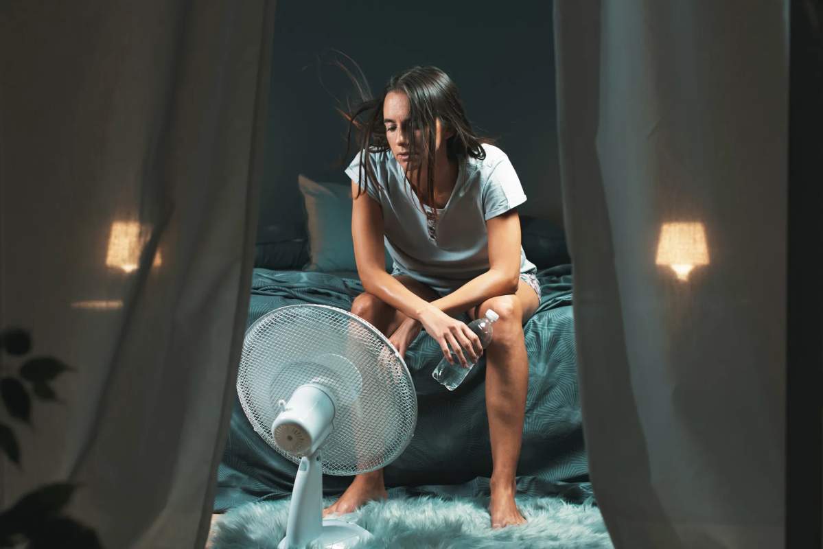 Donna che ha caldo di notte vicino al ventilatore