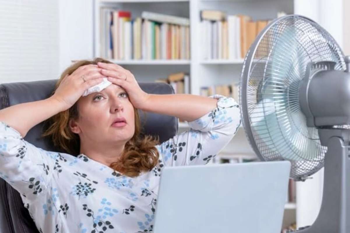 Donna che ha caldo davanti ad n ventilatore acceso